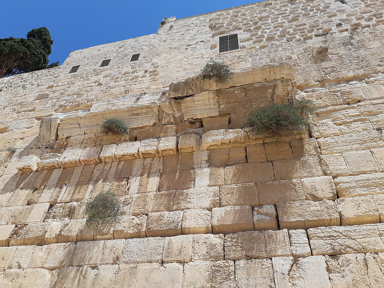 The southwestern corner of the Temple Mount's Herodian retaining wall at the Jerusalem Archaeological Park — massive lower courses of drafted-margin Herodian ashlars, with the projecting spring of Robinson's Arch and smaller later masonry above them.
