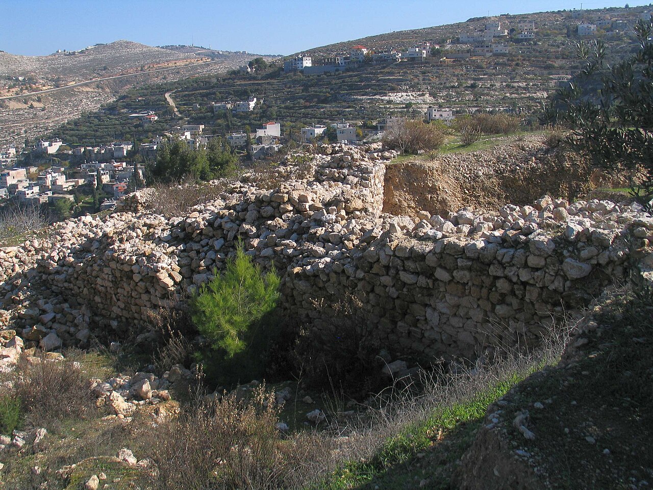 Ruins at Khirbet el-Yahud ("ruin of the Jews") above the village of Battir — the site of ancient Beitar, Bar Kokhba's last stronghold — tumbled stone walls on the hilltop with terraced Judean hills behind.