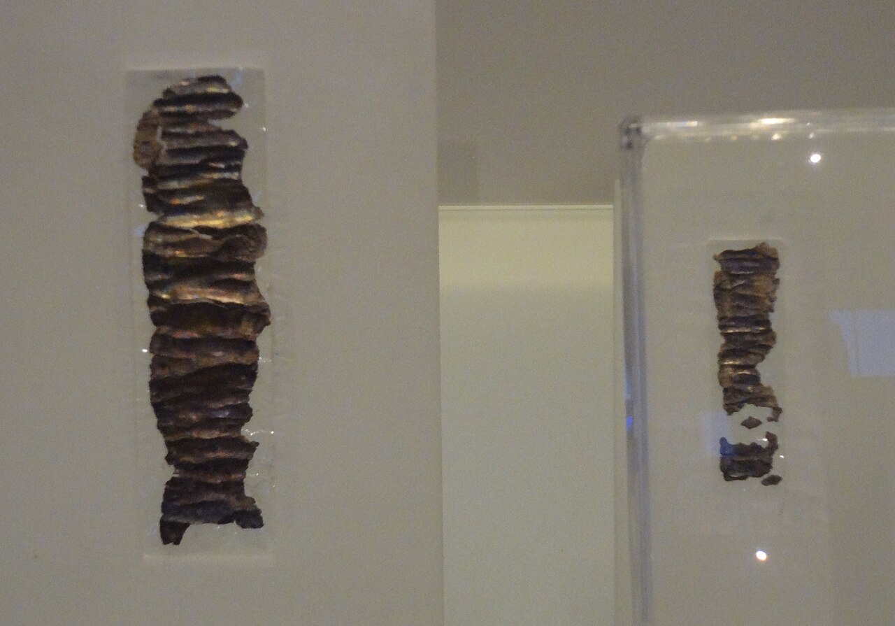The two Ketef Hinnom silver amulets in the Israel Museum — small ribbed strips of dark oxidized silver, unrolled and mounted in clear cases.

