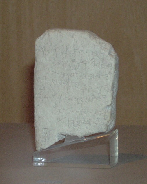 The Gezer Calendar in the Istanbul Archaeology Museums — a small, roughly rectangular limestone tablet scratched with seven uneven lines of early alphabetic letters.
