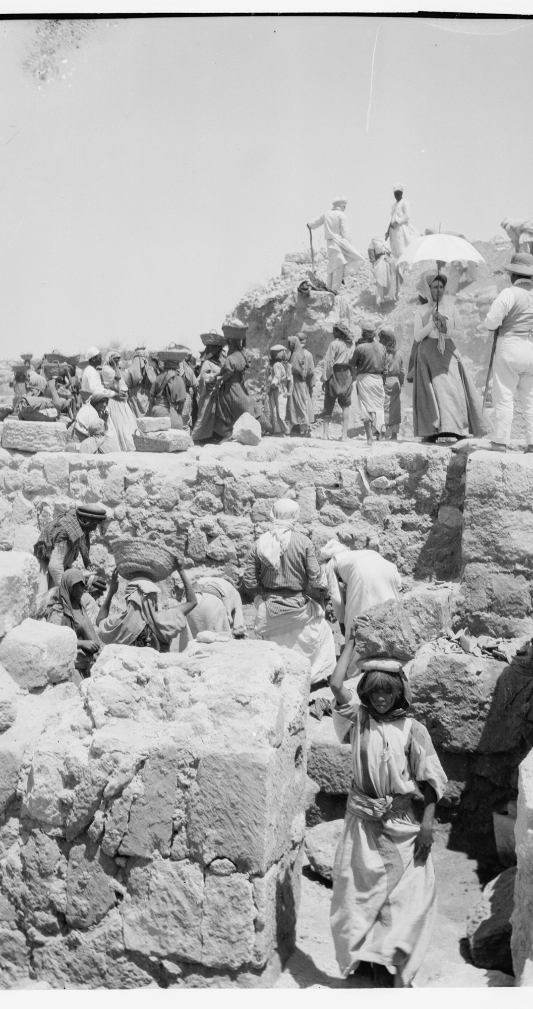 Historic photograph of the Harvard expedition excavating the "Ostraca House" on the acropolis of Shomron — lines of local workers carrying baskets of earth across the stone walls of the dig where the ostraca were found. The sherds themselves are in the Istanbul Archaeology Museums.
