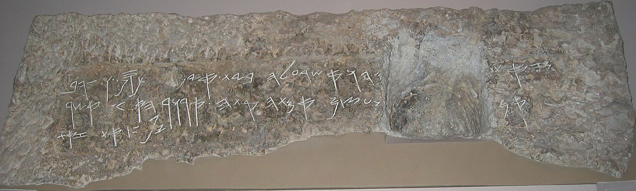The Royal Steward inscription in the British Museum — a long, weathered limestone lintel with three worn lines of paleo-Hebrew letters cut into its face.
