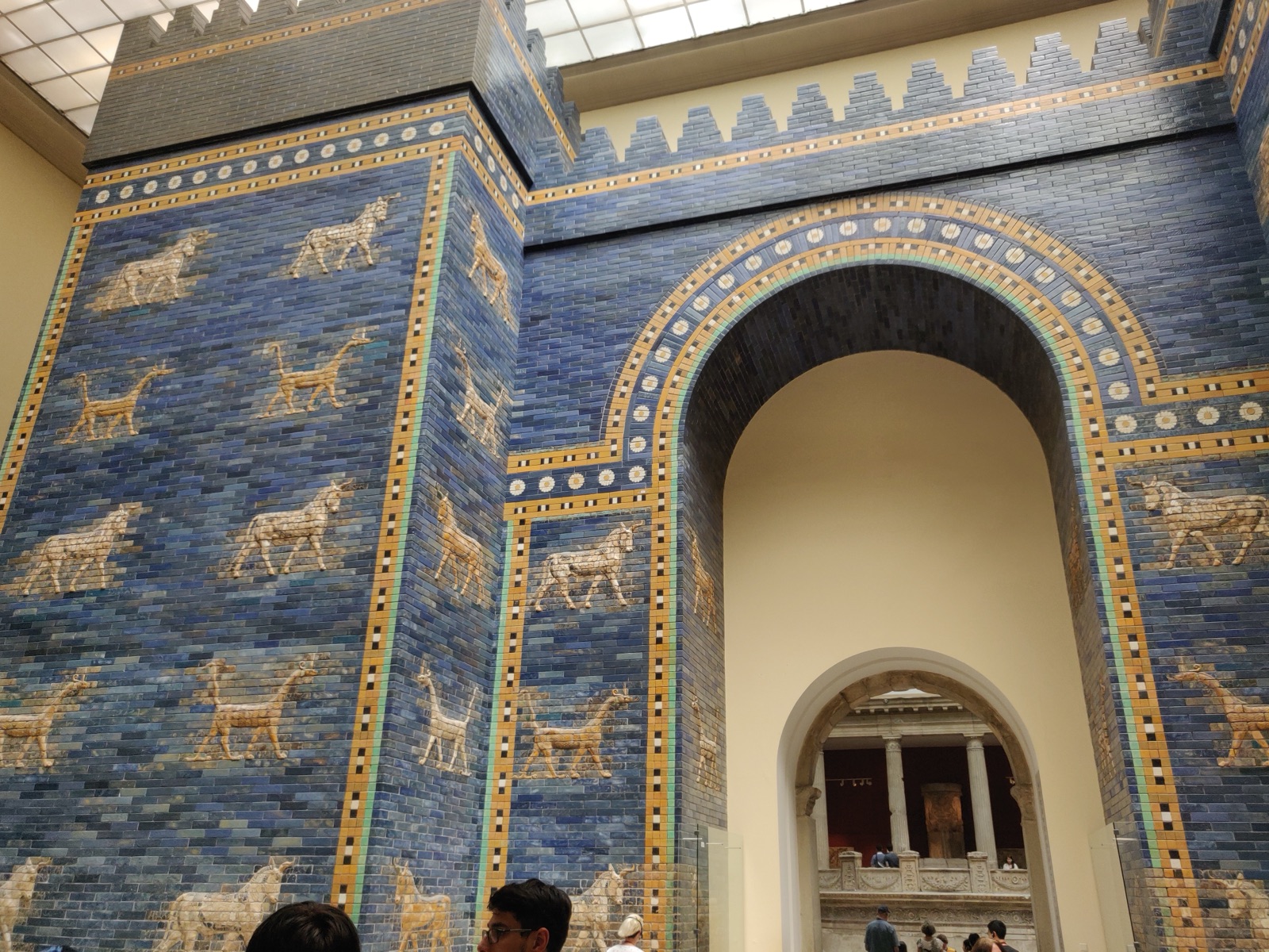 The reconstructed Ishtar Gate in the Pergamonmuseum, Berlin — a towering arch of deep-blue glazed brick decorated with rows of golden aurochs and mushhushshu dragons.
