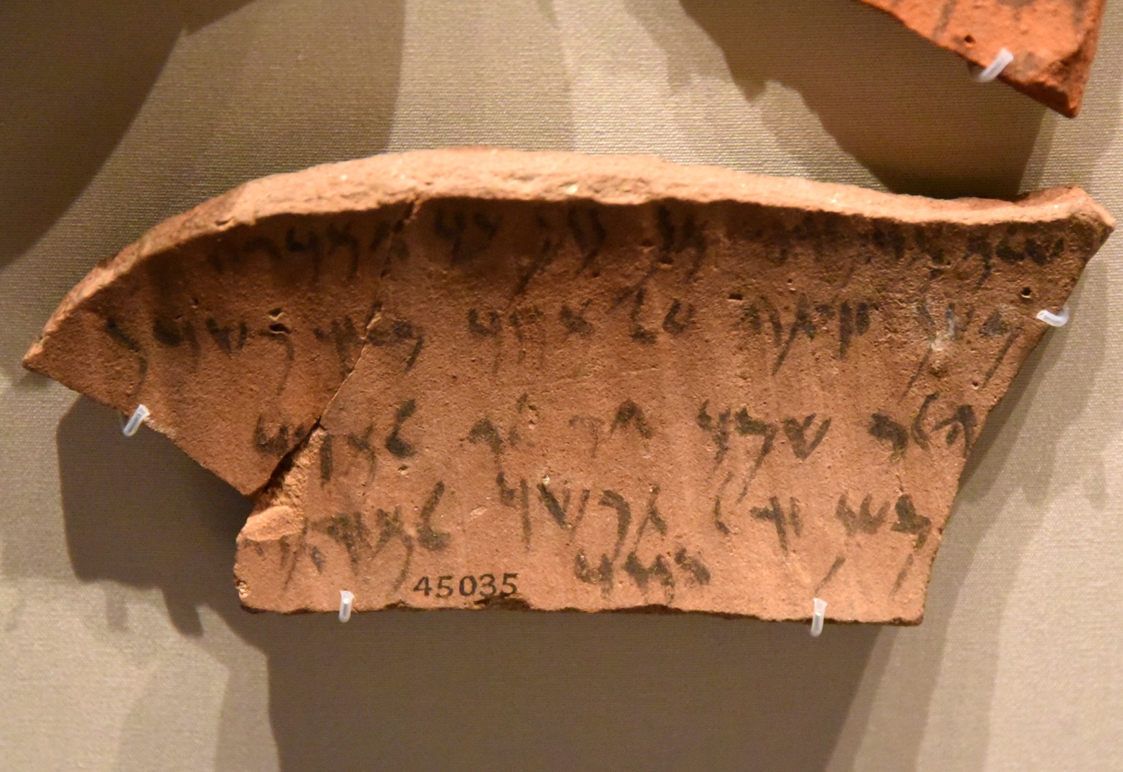 An Aramaic ostracon of the Achaemenid period, probably from Elephantine — five inked lines of Aramaic bearing Jewish names on a curved potsherd (British Museum).
