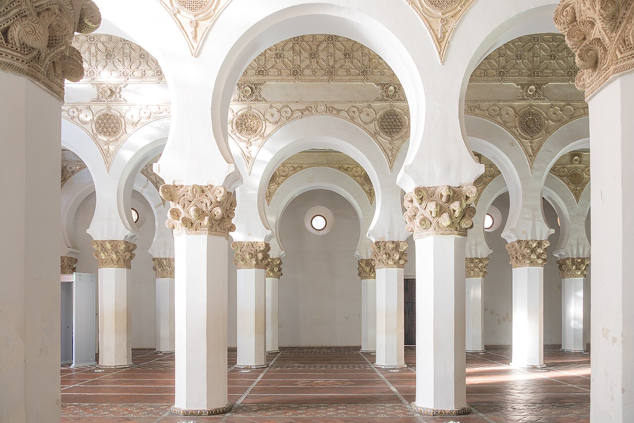 Interior of Santa María la Blanca in Toledo — the whitewashed horseshoe arches, octagonal piers, and carved capitals of the medieval synagogue (built c. 1180, converted to a church in the 15th century).
