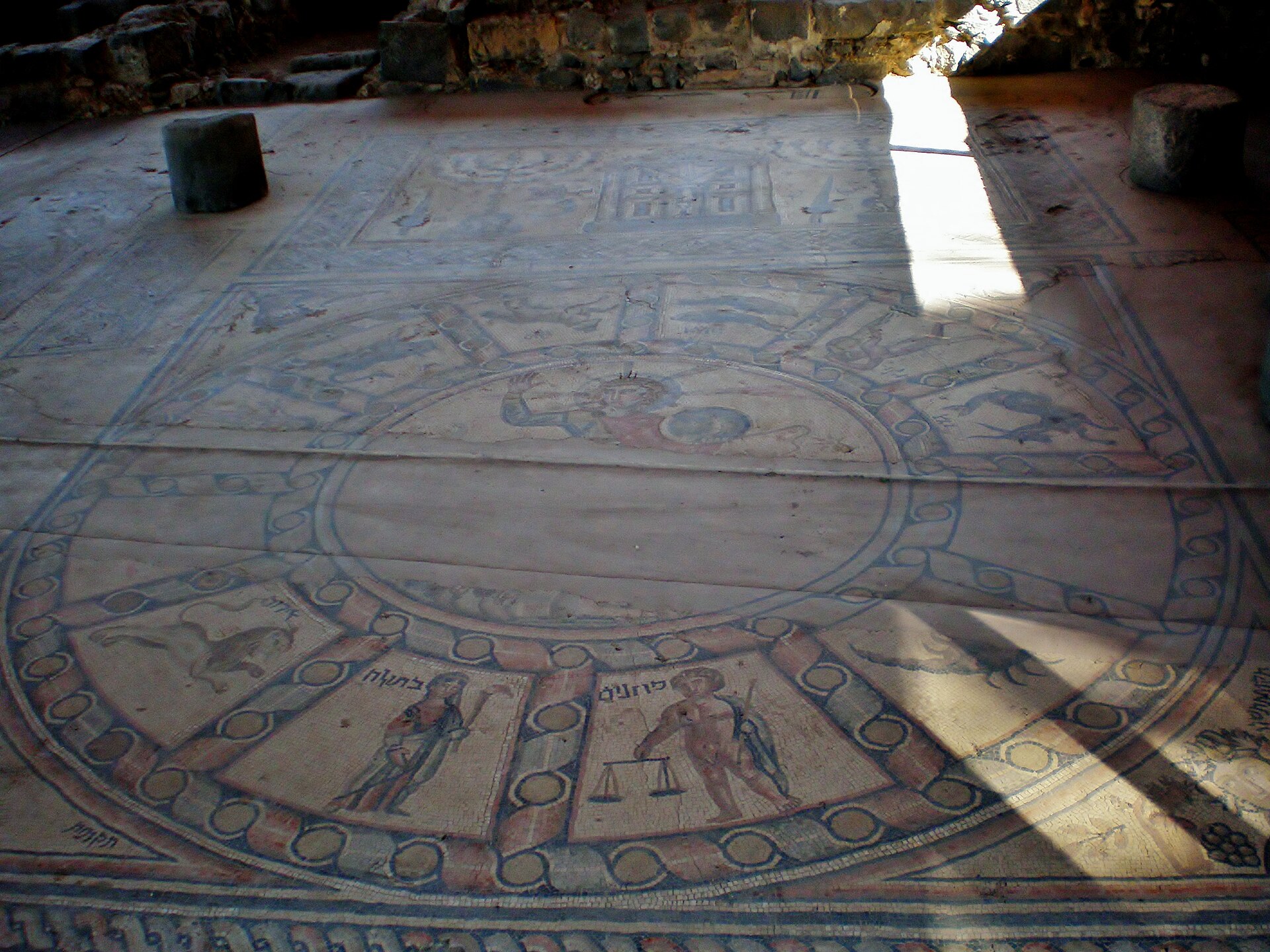 The mosaic floor of the Hammat Tiberias synagogue, showing the zodiac wheel with Helios at its center, Hebrew-labelled zodiac figures around it, and the Torah shrine panel beyond.
